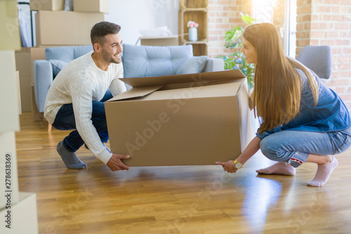 Beautiful young couple moving to a new home, holding big cardboard box © Krakenimages.com