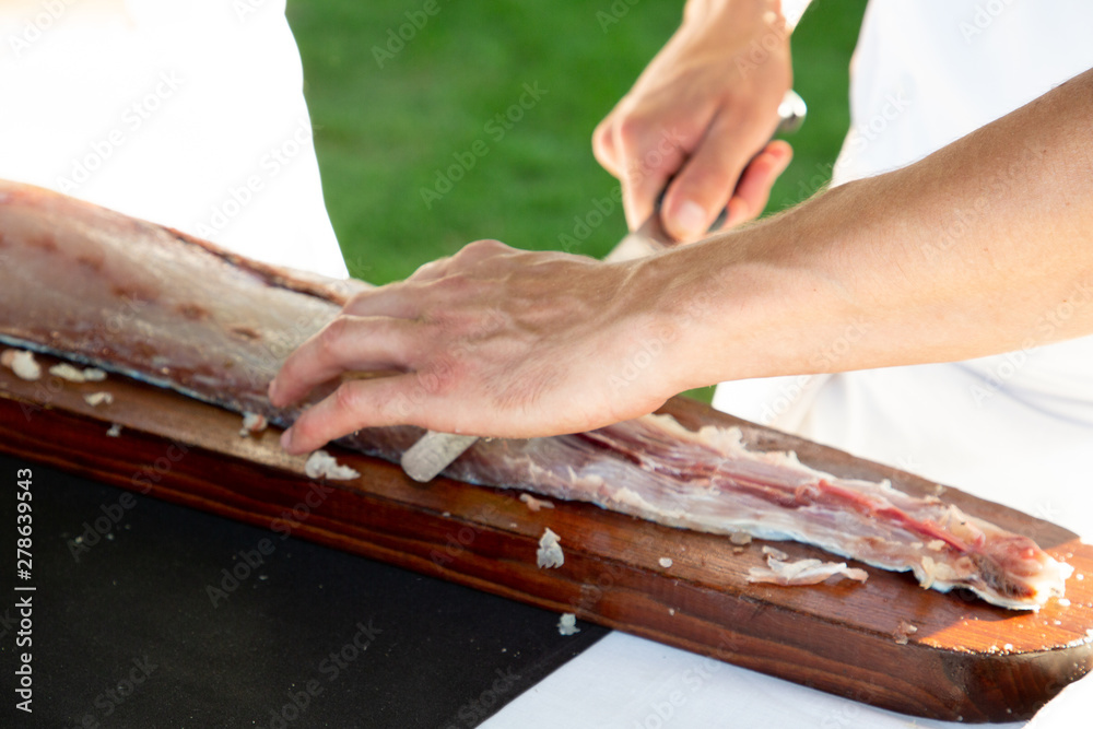 Chef hand cutting fresh piece of salmon