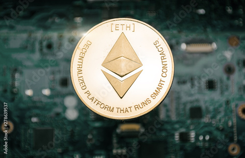 Gold etherum coin, on background of computer motherboard. photo