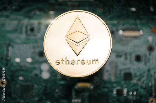 Gold etherum coin, on background of computer motherboard. photo