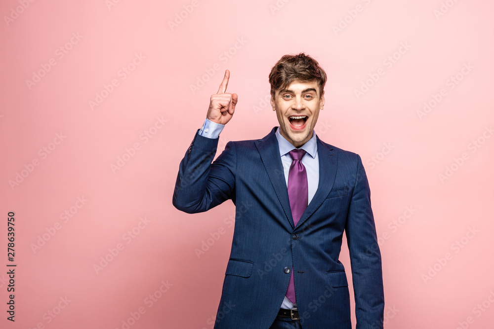 happy businessman showing idea sign and looking at camera on pink background happy businessman showing idea sign and looking at camera on pink background
