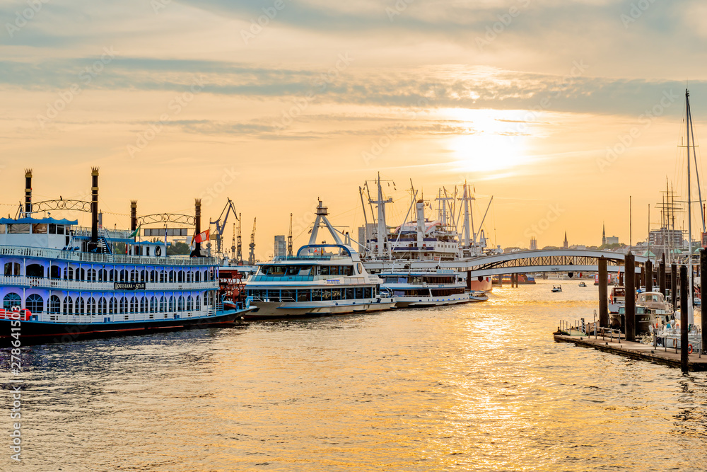 Fototapeta premium Cruise ships standing at the marina in Hamburg, on the river Elbe. Sunset over the river Elbe.