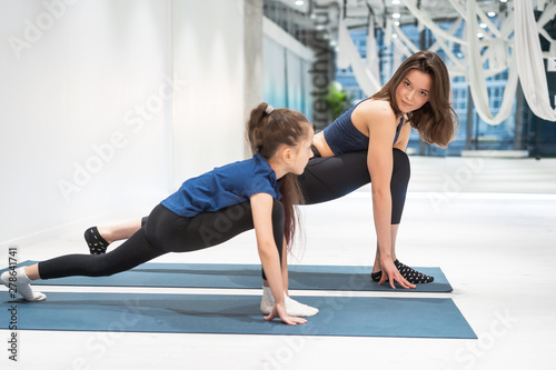 Young adult mom and little daughter together on aerobics