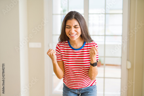 Young beautiful woman wearing casual t-shirt very happy and excited doing winner gesture with arms raised, smiling and screaming for success. Celebration concept.