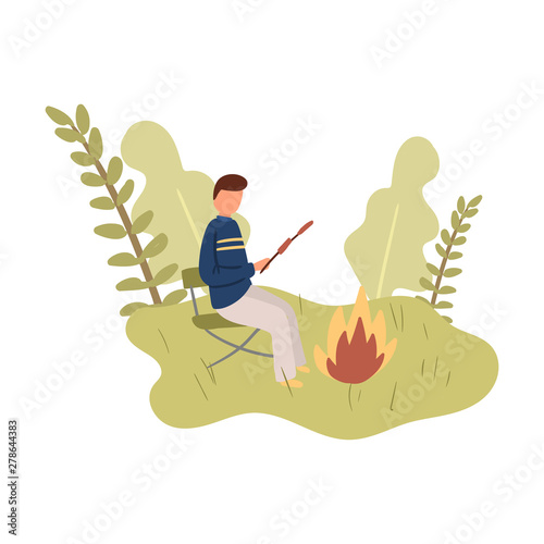 Young boy stay on chair and cook marshmallow on campfire