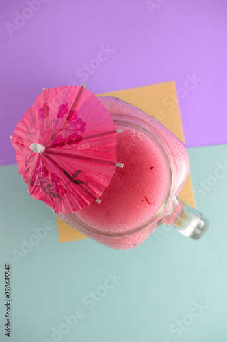 Pink, summer cocktail of fresh fruits on a blue and purple background. Refreshing drink in summer