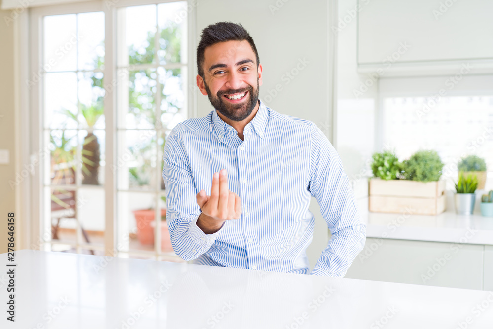 Handsome hispanic business man Beckoning come here gesture with hand inviting happy and smiling