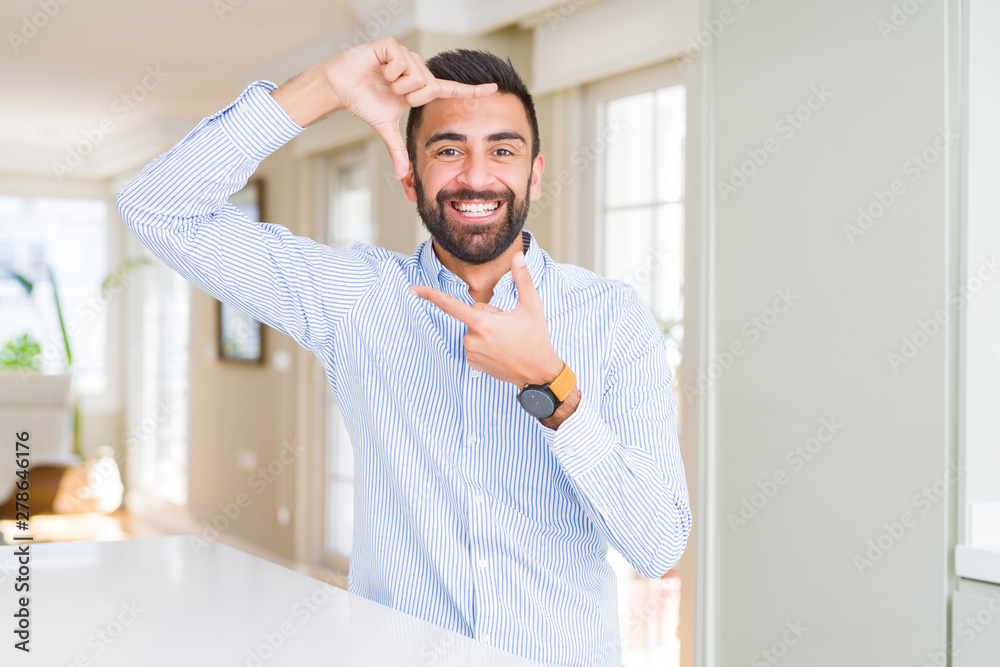 Handsome hispanic business man smiling making frame with hands and fingers with happy face. Creativity and photography concept.