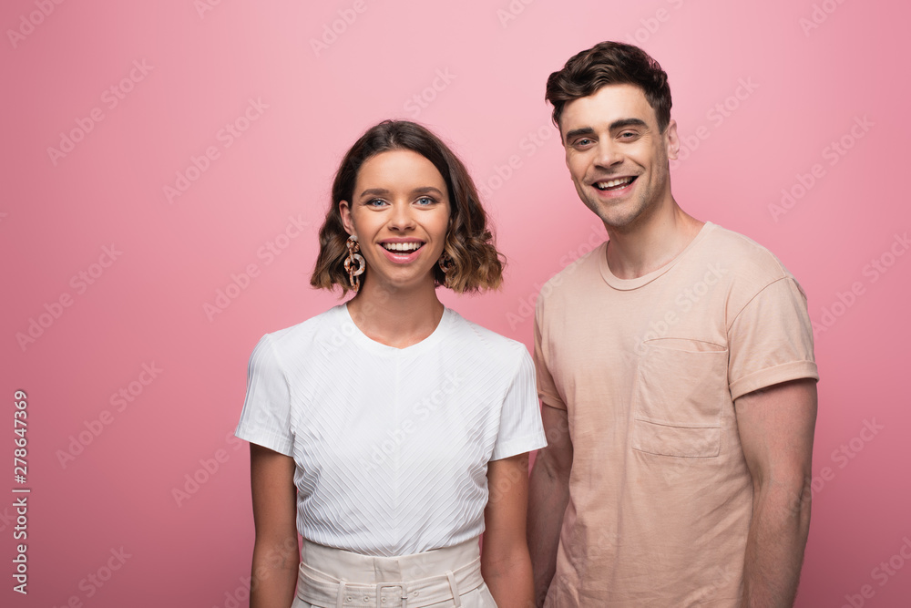 young, cheerful man and woman looking at camera on pink background young, cheerful man and woman looking at camera on pink background