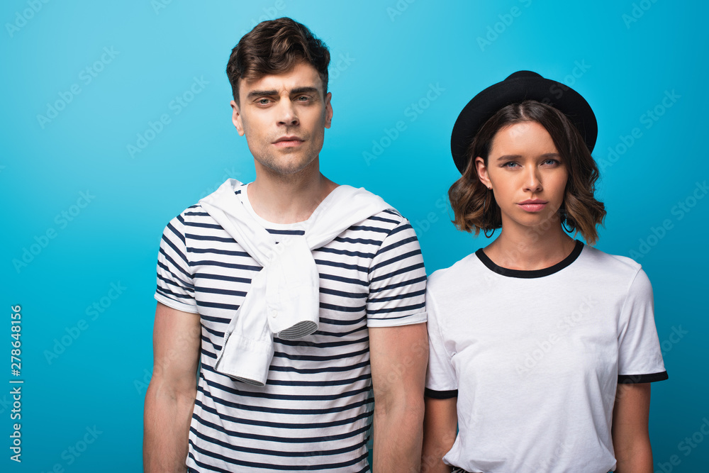 young, disappointed man and woman looking at camera on blue background young, disappointed man and woman looking at camera on blue background