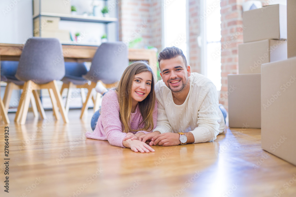 Young beautiful couple in love moving to new home, lying on the floor around cardboard boxes, very happy and cheerful for new apartment Young beautiful couple in love moving to new home, lying on the floor around cardboard boxes, very happy and cheerful for new apartment
