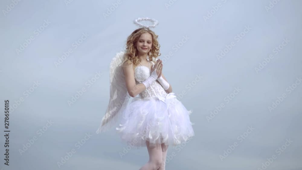 Angel wings baby pray. Love concept. Cute teen cupid on the cloud - heaven background. Angel child girl with curly blonde hair - Innocent girl concept. Pray. Angel wings baby pray. Love concept. Cute teen cupid on the cloud - heaven background. Angel child girl with curly blonde hair - Innocent girl concept. Pray.