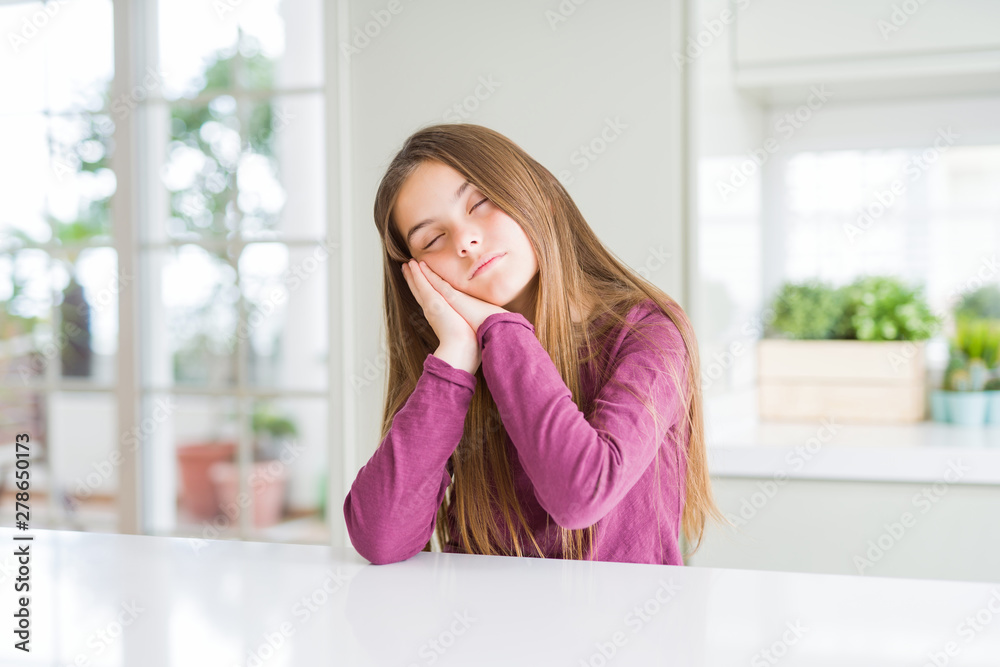 Beautiful young girl kid on white table sleeping tired dreaming and posing with hands together while smiling with closed eyes. Beautiful young girl kid on white table sleeping tired dreaming and posing with hands together while smiling with closed eyes.