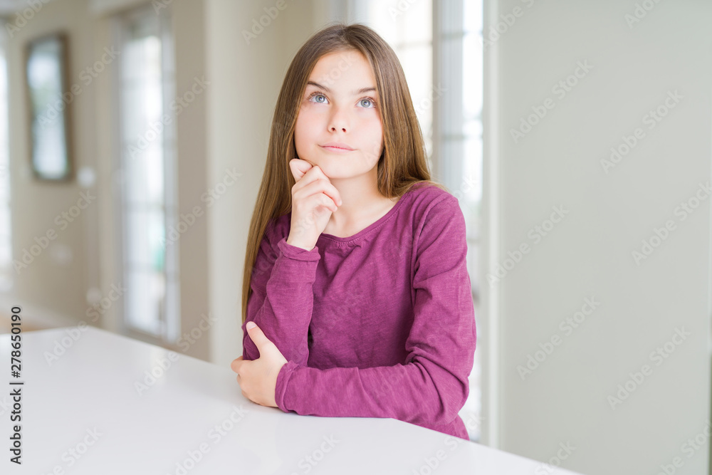 Beautiful young girl kid on white table with hand on chin thinking about question, pensive expression. Smiling with thoughtful face. Doubt concept. Beautiful young girl kid on white table with hand on chin thinking about question, pensive expression. Smiling with thoughtful face. Doubt concept.