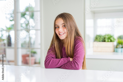 Free Download Beautiful young girl kid on white table happy face smiling with crossed arms looking at the camera. Positive person. - GFXLoad
