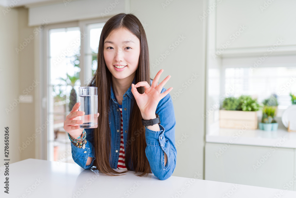 Beautiful Asian woman drinking a glass of fresh water doing ok sign with fingers, excellent symbol Beautiful Asian woman drinking a glass of fresh water doing ok sign with fingers, excellent symbol