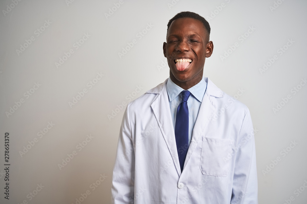 Young african american doctor man wearing coat standing over isolated white background sticking tongue out happy with funny expression. Emotion concept. Young african american doctor man wearing coat standing over isolated white background sticking tongue out happy with funny expression. Emotion concept.