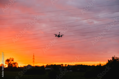 Custom made drone flying on sunset near power lines. Concept modeling, detection of obstacles