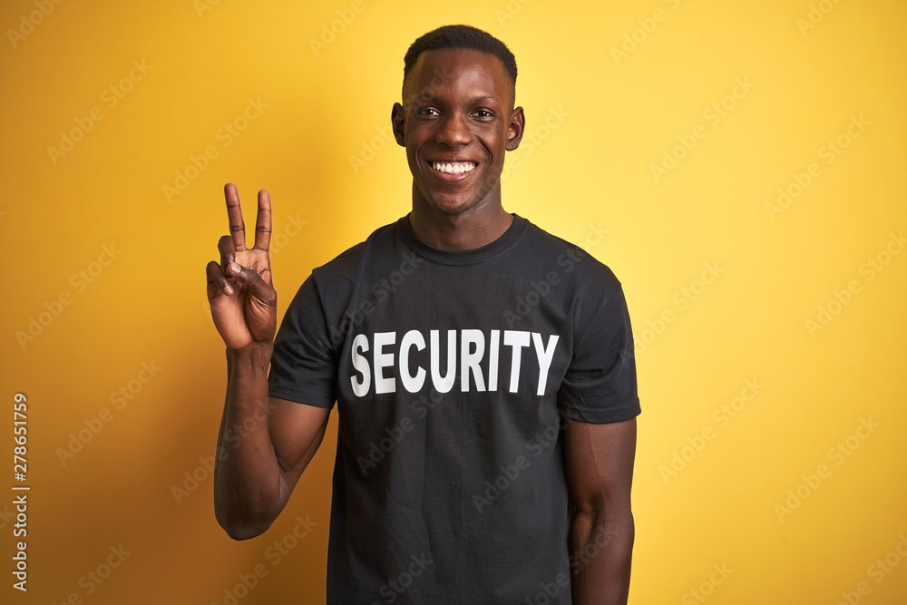 African american safeguard man wearing security uniform over isolated yellow background showing and pointing up with fingers number two while smiling confident and happy. - obrazy, fototapety, plakaty 