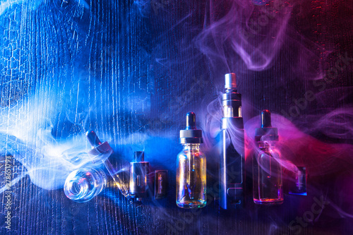 E-cigarette liquids.Vape.Accessories for Smoking. Electronic devices for Smoking.Smoking gadgets.Electronic cigarette and liquid bottles. Kit for vaping on a blue-purple background. Cigarette smoke Stock Photo - Adobe Stock