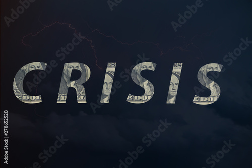 The word crisis written from elements of a dollar bill on a blurred gloomy thunderstorm hurricane sky, toned. photo