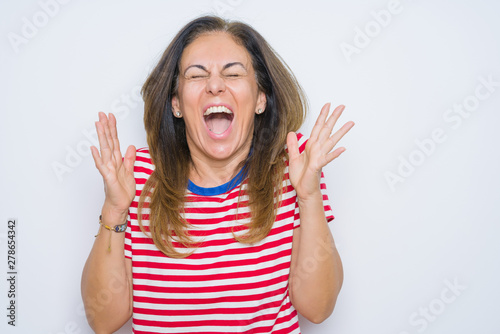 Middle age senior woman standing over white isolated background celebrating mad and crazy for success with arms raised and closed eyes screaming excited. Winner concept