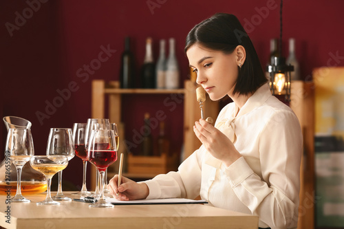 Young female sommelier working in wine cellar photo