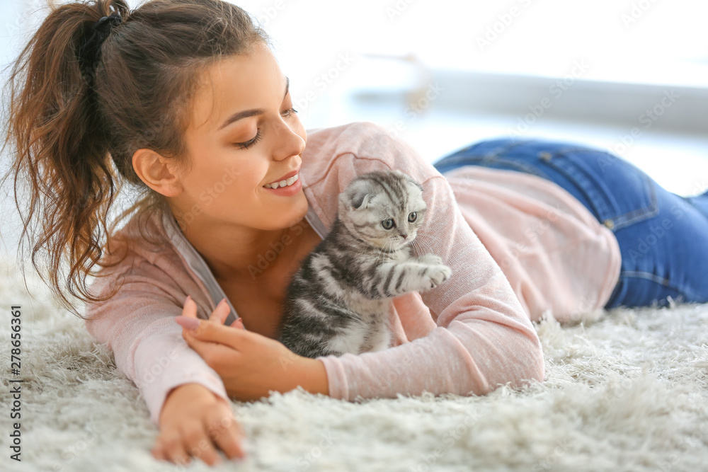 Beautiful young woman with cute little kitten at home - obrazy, fototapety, plakaty 