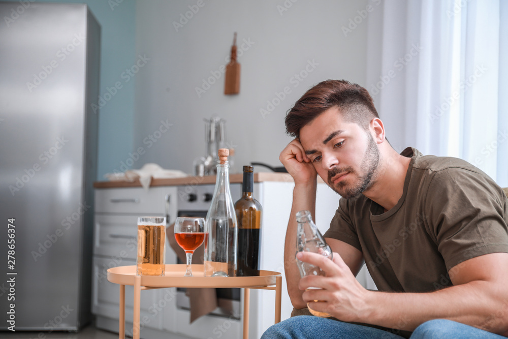 Young man with addiction to alcohol drinking beer at home Young man with addiction to alcohol drinking beer at home