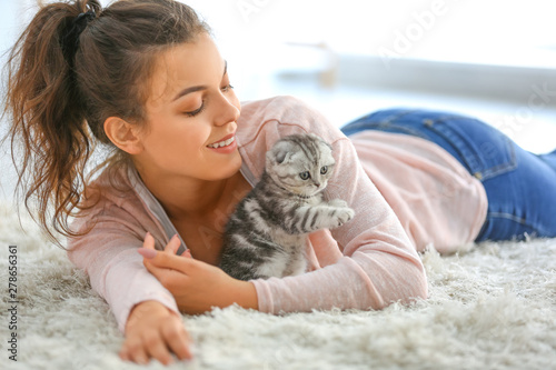 Photo Beautiful young woman with cute little kitten at home