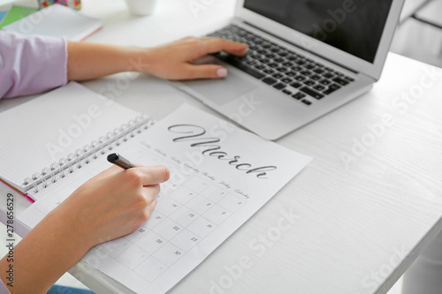 Young woman marking date in...
