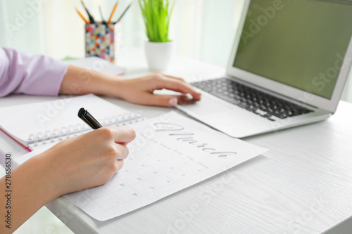 Young woman marking date in...