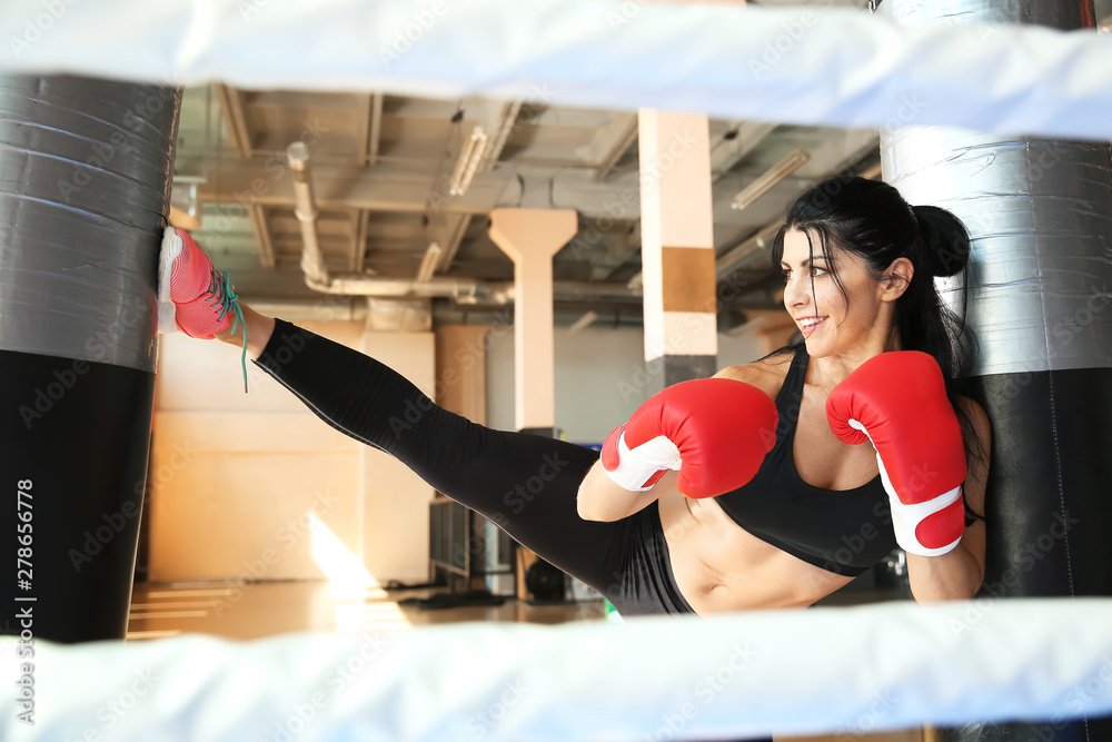 Female kickboxer training with punching bag in gym Female kickboxer training with punching bag in gym