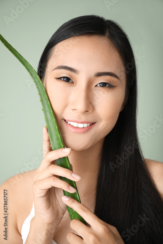 Beautiful Asian woman with aloe vera on color background