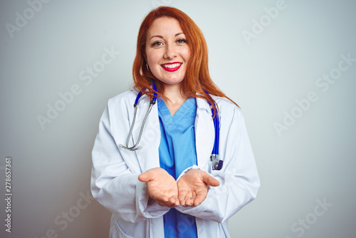 Young redhead doctor woman using stethoscope over white isolated background Smiling with hands palms together receiving or giving gesture. Hold and protection