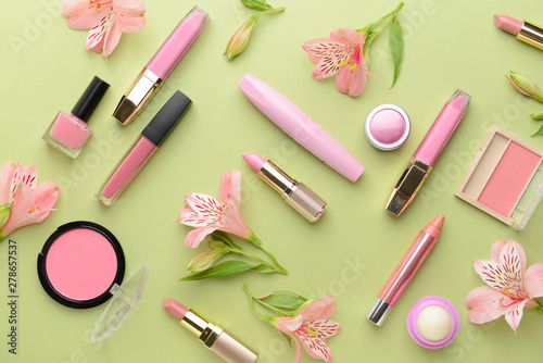 Set of decorative cosmetics and flowers on color background