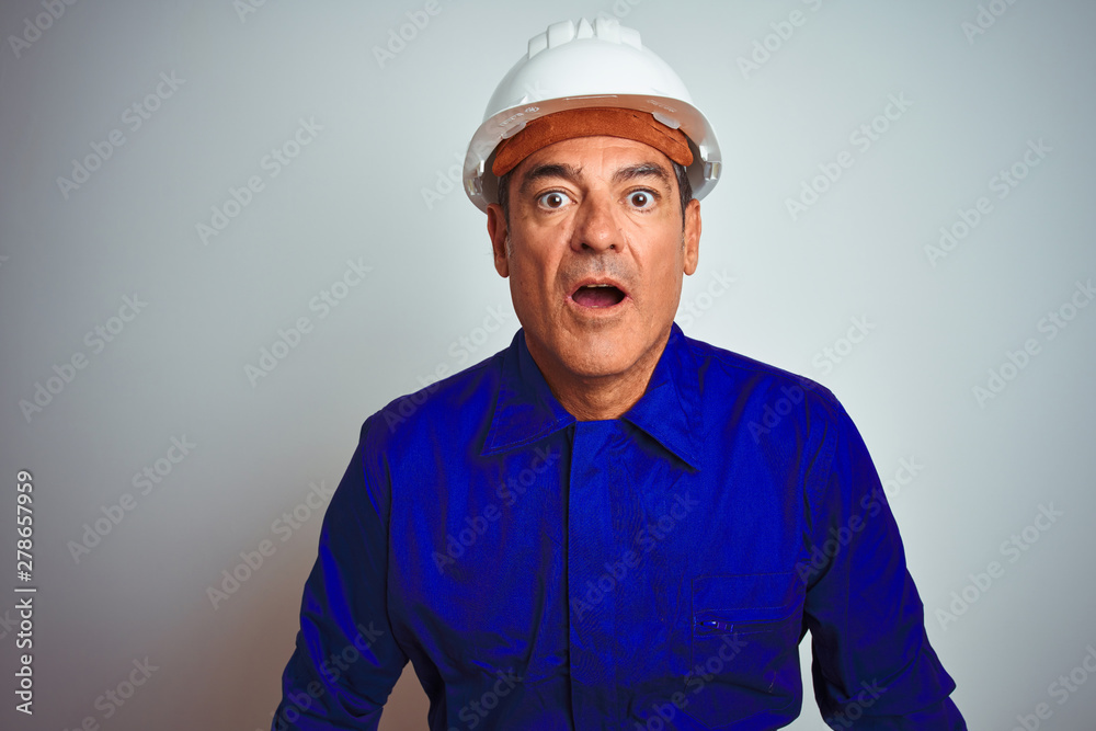 Handsome middle age worker man wearing uniform and helmet over isolated white background afraid and shocked with surprise expression, fear and excited face. Handsome middle age worker man wearing uniform and helmet over isolated white background afraid and shocked with surprise expression, fear and excited face.