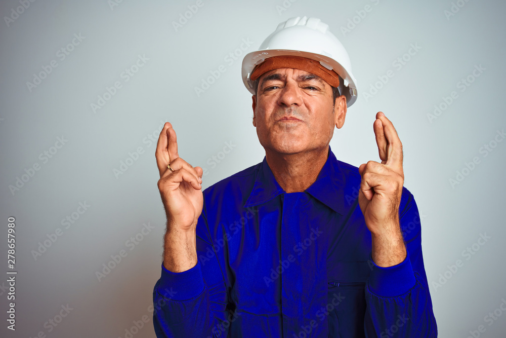 Handsome middle age worker man wearing uniform and helmet over isolated white background with sad expression covering face with hands while crying. Depression concept.
