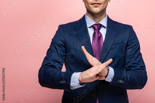 Φωτογραφία cropped view of businessman in formal wear showing reject gesture on pink backgr