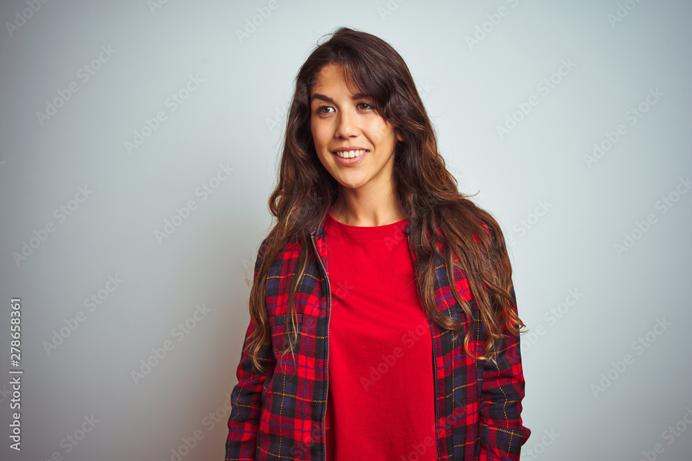 Young beautiful woman wearing red t-shirt and jacket standing over white isolated background looking away to side with smile on face, natural expression. Laughing confident. Young beautiful woman wearing red t-shirt and jacket standing over white isolated background looking away to side with smile on face, natural expression. Laughing confident.