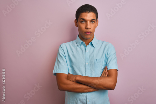 Young handsome arab man wearing blue shirt standing over isolated pink background skeptic and nervous, disapproving expression on face with crossed arms. Negative person.