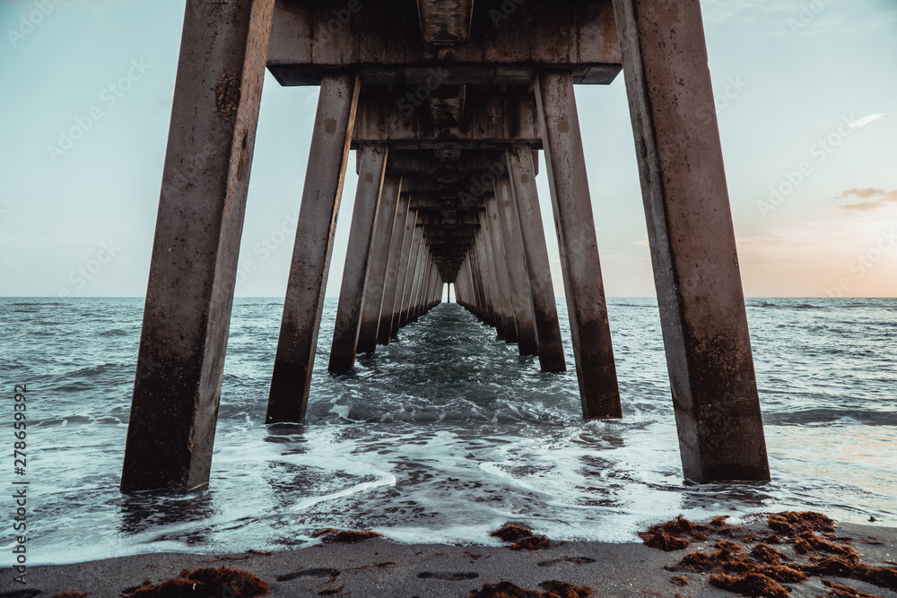 Wide angle single point symmetry under a pier on the tropical coastline, waves