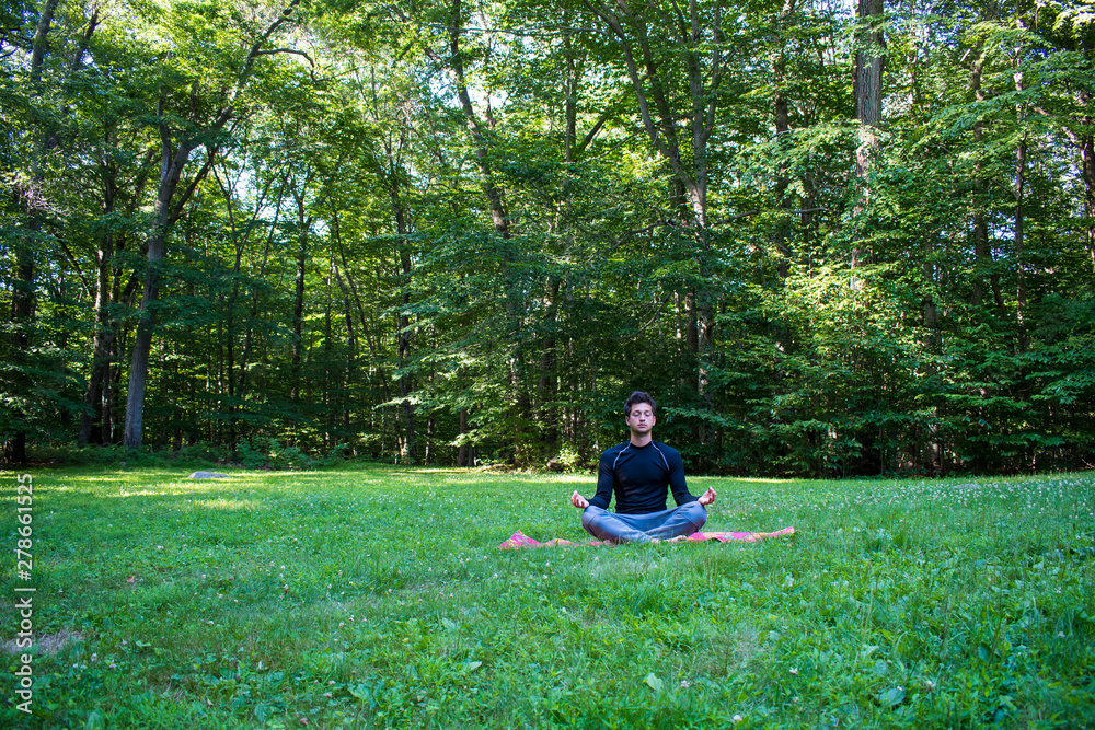 Young male meditating in beautiful outdoor park Young male meditating in beautiful outdoor park