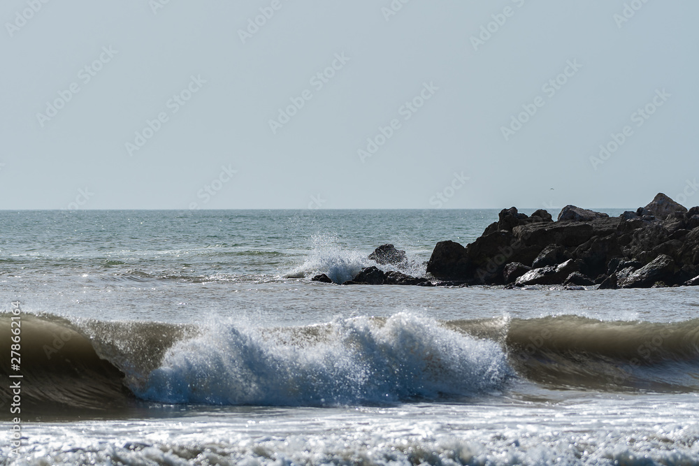 Beach view with waves and a rocky outpoint in Florida