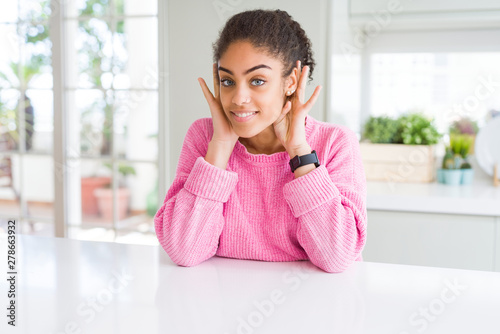Beautiful african american woman with afro hair wearing casual pink sweater Trying to hear both hands on ear gesture, curious for gossip. Hearing problem, deaf Free Download Beautiful african american woman with afro hair wearing casual pink sweater Trying to hear both hands on ear gesture, curious for gossip. Hearing problem, deaf - GFXLoad