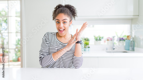 Beautiful african american woman with afro hair wearing casual striped sweater clapping and applauding happy and joyful  smiling proud hands together