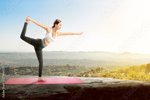 Asian healthy woman practicing yoga on the carpet on rock