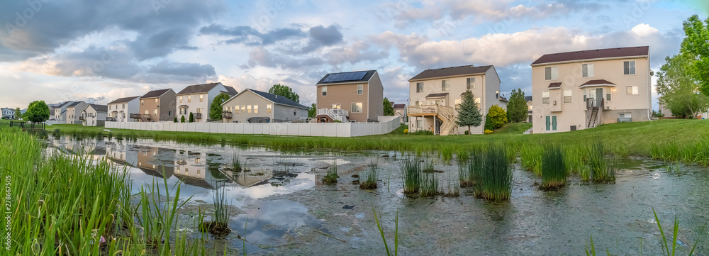Beautiful multi storey homes built in front of a grassy and shiny pond