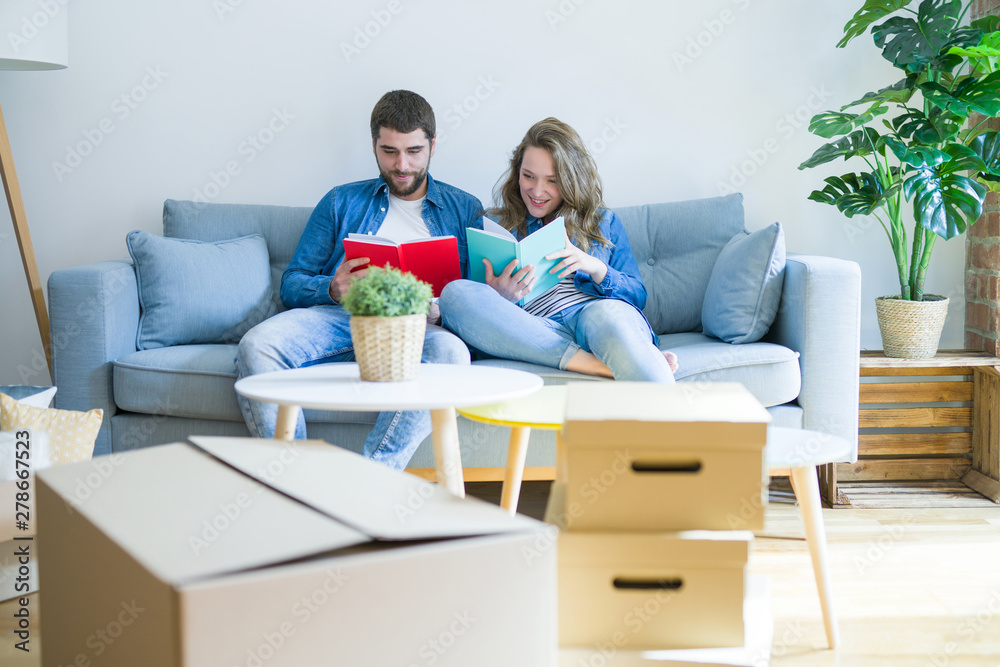 Young couple relaxing on the sofa reading a book, taking a break for moving to new house Young couple relaxing on the sofa reading a book, taking a break for moving to new house