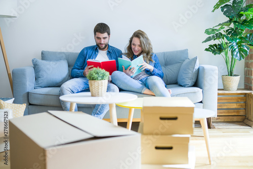 Young couple relaxing on the sofa reading a book, taking a break for moving to new house
